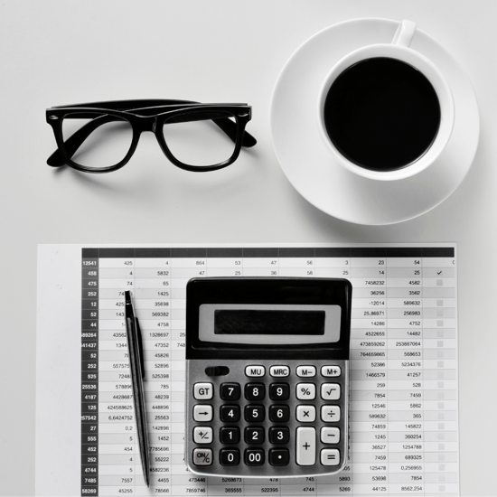 flat lay image of black glasses, a coffee and a notepad, pen and calculator