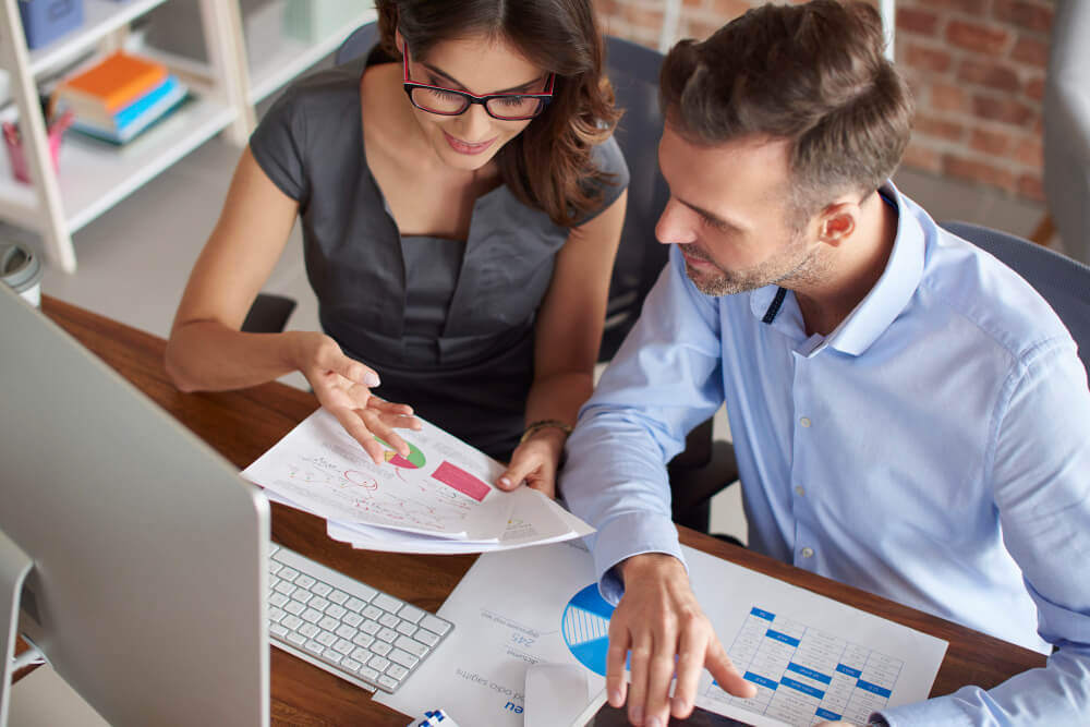 woman explaining a report to a man sitting beside her