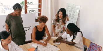 a group of 5 women sitting around a desk