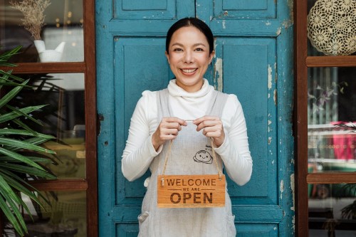 woman holding a We are Open sign outside her storefront