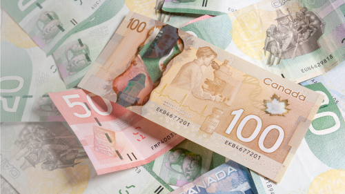 Close-up of a Canadian $100 bill with other $50 and $20 bills in the background.